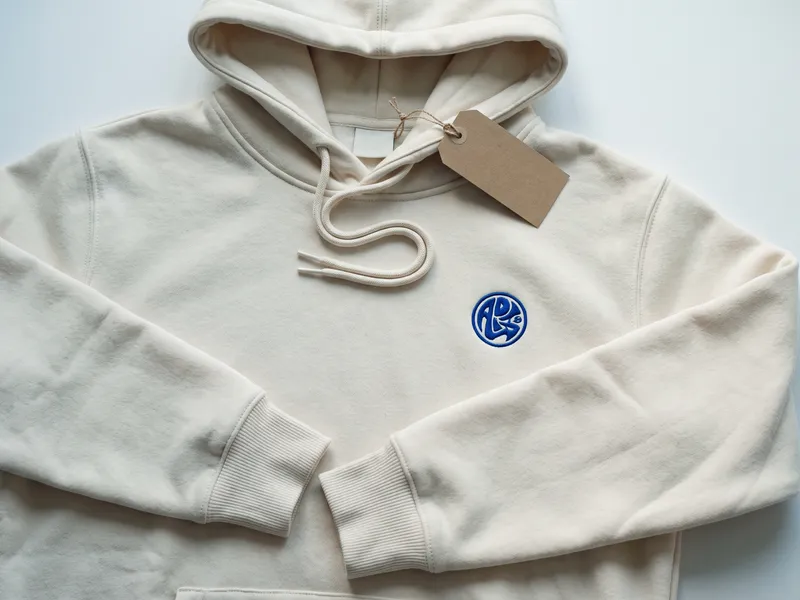 Heavyweight cream custom hoodie with embroidered cobalt chest emblem