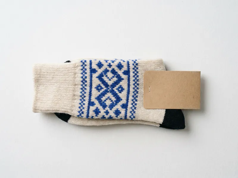 Folded custom knit crew socks with cobalt woven pattern and black heel